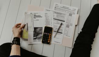 person holding paper near pen and calculator by Kelly Sikkema courtesy of Unsplash.